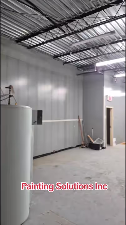 Chantier commercial de Painting Solutions : grand espace avec colonnes et plafond ouvert.